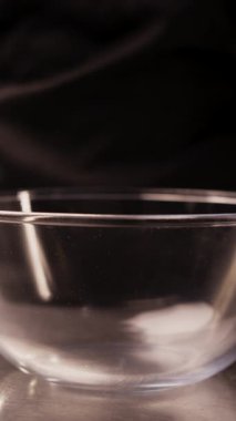 Yakın planda çekilen randevular şeffaf bir cam kaseye düşüyor. Hurma ağacının tomurcuğundan sarkan olgun hurma lifleri ve besinlerle doludur..