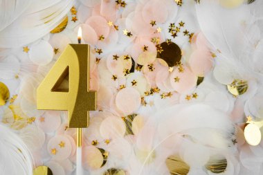 Dördüncü Doğum Günü Kutlaması Altın Mum ve Konfeti ile. Pastel renkli konfeti, altın yıldız şekilleri ve beyaz tüy arkaplan arasında altın rakamlı dört doğum günü mumu..