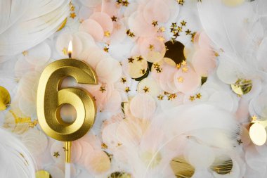Altıncı Doğum Günü Kutlaması Altın Mum ve Konfeti ile. Pastel renkli konfeti, altın yıldız şekilleri ve beyaz tüy arkaplan arasında altın rakamlı altı doğum günü mumu..