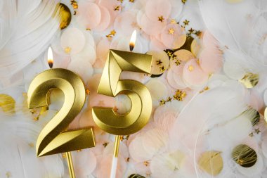 Altın Mum ve Konfeti ile 25. doğum günü kutlaması. Pastel renkli konfeti, altın yıldız şekilleri ve beyaz tüyler arasında altın rakamlı 25 yaş günü mumu..