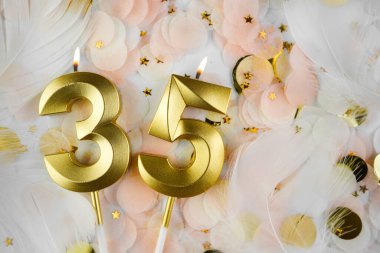 35. yaş günü kartı. 35 numaralı altın mumlar, pastel konfeti arka planında 35 numara. Yıldönümü ve doğum günü konsepti. Boşluğu kopyala.