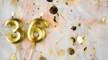 36. yaş günü kartı. 36 numaralı altın mumlar, pastel konfeti arka planında 36 numara. Yıldönümü ve doğum günü konsepti. Boşluğu kopyala.