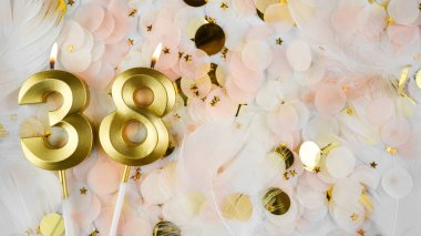 38. yaş günü kartı. 38 numaralı altın mumlar, pastel konfeti arka planında 38 numara. Yıldönümü ve doğum günü konsepti. Boşluğu kopyala.
