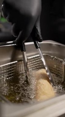 Tempura hamuru ve kızgın yağda ekmek kırıntılarıyla kaplanmış şefin yakın çekimi. Kızarmış shawarma 'nın adım adım tarifi. Fast food konsepti. dikey video