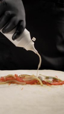 Adım adım shawarma tarifi. Şefin elleri taze malzemelerin üzerine ince lavaş ambalajıyla mayonez serpiyor. Türk mutfağı ve fast food hazırlığı kavramı. Dikey video