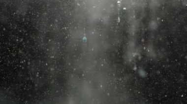 Siyah zemin üzerinde suya batan beyaz toz parçacıklarının yavaş hareketi bulutlu soyut bir doku yaratıyor. Kirlilik kavramı, ince enkaz, hareket ve su altı parçacıkları.