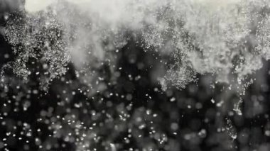 Siyah zemin üzerinde suya düşen küçük beyaz parçacıkların makro görüntüsü gizemli ve soyut hareketler yaratıyor. Saflık, karşıtlık, doku ve akıcılık kavramı.