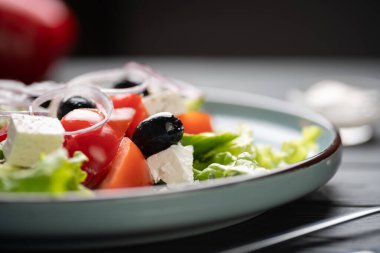 Domatesli, salatalıklı, zeytinli ve ahşap kaplama salatalı Yunan salatasını yakın. Vejetaryen sağlıklı gıda konsepti. Boşluğu kopyala