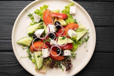 Sulu domatesli canlı Yunan salatası, çıtır salatalık, siyah zeytin, taze peynir ve karışık marul yaprakları. Renkli ve doğal aromalı geleneksel sağlıklı yemekler. en üstteki görünüm