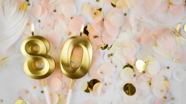 80. yaş günü kartı. 80 numaralı altın mumlar, pastel konfeti arka planında seksen numara. Yıldönümünü ve doğum gününü kutluyoruz. Boşluğu kopyala.