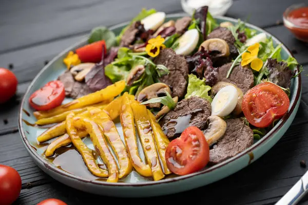 Izgara biberli taze sebze salatası, sıcak sığır eti dilimleri, mantarlar, balzamik jöle, marul ve beyaz tabakta haşlanmış yumurta. Sağlıklı yemek konsepti. Üst görünüm.