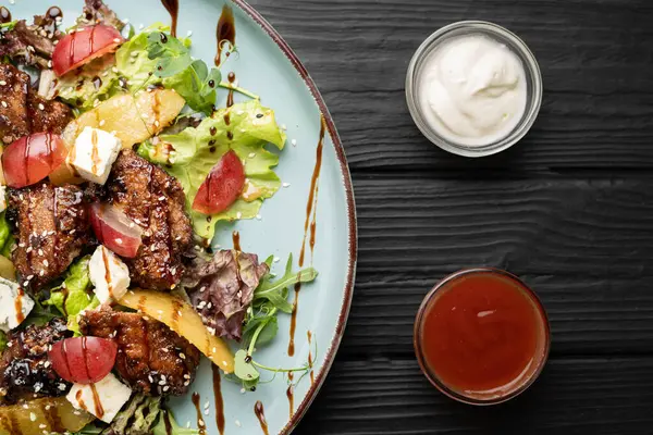 Tavuk ciğeri, kavrulmuş armut, yumuşak mavi peynir, üzümler ve balzamik jöleli yapraklı yeşillikler içeren restoran tarzı salata. Gurme yemek tabağı kavramı. Üst görünüm