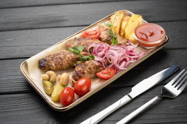 Geleneksel Türk yemeği. Kızarmış lula kebabı, salamura soğan, ızgara domates, mantar, ketçap ve ahşap masada kızarmış patates dilimleri ile birlikte sıcak servis edilir. Üst görünüm