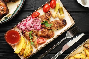 Lezzetli ızgara şiş kebap. Terbiye edilmiş soğanlar, ızgara mantarlar, çıtır patatesler, domatesler ve ketçapla birlikte Türk lokantasında kırsal ahşap masada servis edilir. Üst görünüm