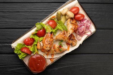 Tabakta kızarmış tavuk, marul yaprakları, dilimlenmiş domatesler ve baharatlı ketçap. Geleneksel Alman usulü akşam yemeği. Ahşap yüzeyde kırsal gıda sunumu. Uzayı kopyala Üst görünüm