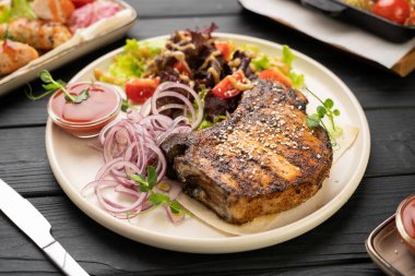 Baharatlı soğan, taze salata ve vişneli domatesli ızgara domuz bifteği. Restoran yemeği konsepti, ızgara et, akşam yemeği menüsü için mükemmel. Boşluğu kopyala