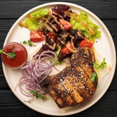 Salamura edilmiş kırmızı soğanlı sulu domuz eti, taze domates dilimleri ve yapraklı sebze salatası. Izgara et yemeği fikri. Lezzetli bir restoran tarzı sunum. Üst görünüm, yakın çekim