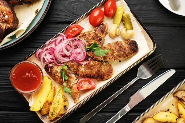 Lezzetli ızgara şiş kebap. Terbiye edilmiş soğanlar, ızgara mantarlar, çıtır patatesler, domatesler ve ketçapla birlikte Türk lokantasında kırsal ahşap masada servis edilir. Üst görünüm