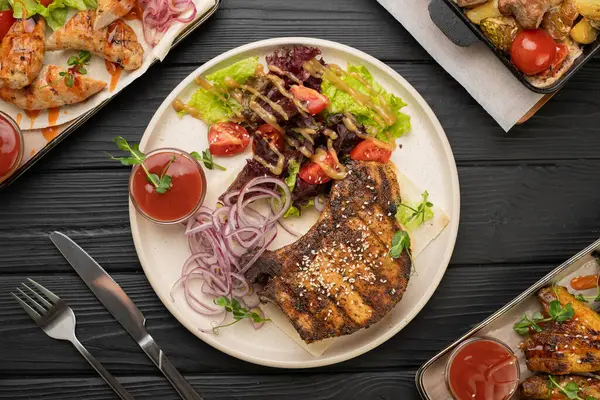 Mükemmel ızgara domuz eti, renkli sebze salatası, kiraz domatesleri ve soğan turşusuyla servis edilir. Lezzetli yemek ve lezzetli yemek kavramı. Üst görünüm