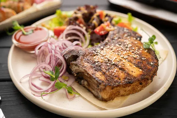 Karışık salata, marine edilmiş soğan ve sulu vişneli domatesli ızgara domuz eti. Yürekli akşam yemeği konsepti, ev yapımı ya da restoran yemeği, köy tarzı. Yakın plan.