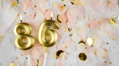 86. yaş günü kartı. 86 numaralı altın mumlar, Pastel Konfeti arka planında 86 numara. Yıldönümünü ve doğum gününü kutluyoruz. Boşluğu kopyala.