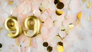 99 'uncu yaş günü kartı. 99 numaralı altın mumlar. Pastel konfeti arka planında 99 numara. Yıldönümünü ve doğum gününü kutluyoruz. Boşluğu kopyala.