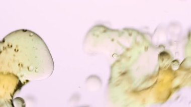 Yağ akıyor ve su altında hareket halinde kabarcıklar oluşturuyor. Su, sıvı doku ve hareket konsepti ile harmanlanmış yüzen altın damlalar ve yağlı girdaplar soyut makro çekim