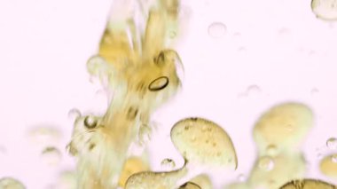 Altın yağ temiz beyaz arkaplanda suya dökülür soyut kabarcıklar ve organik girdaplar oluşturur yavaş çekimde. Sıvı hareketi ve sıvı dinamiği makro doku kavramı.