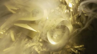 20 numara şeklindeki altın mumlar kayan dumanlarda parlayan folyo arka planına konur. Doğum günü ya da yıl dönümü kutlamaları için şık bir konsept.