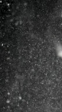 Yavaş çekim tozu ve toz parçacıkları suya düşüyor, sualtı makro çekimi koyu siyah arkaplanlı. Sıvıdaki bulanık hareketin soyut dokusu ve organik bulut oluşumu.