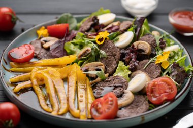 Kavrulmuş biber, olgun domates, topraksı mantar karışımı üzerinde cızırdayan sığır madalyonları. Lokantada lezzetli bir menü için servis ediliyor..