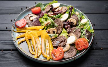 Sıcak et parçaları, ızgara tatlı biberle harmanlanmış taze domates, tabakta lezzetli mantar, ahşap zemin üzerinde sağlıklı kırsal yemek için..