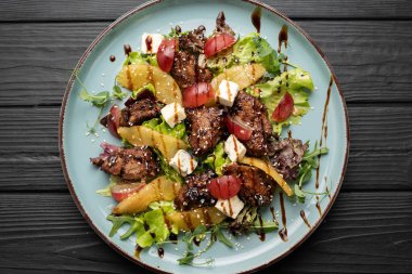 Sıcak kızarmış tavuk ciğeri, tatlı üzüm, keskin mavi peynir, zengin et menüsü için tabakta karamelize armut. Üst görünüm