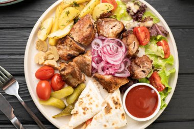Kızarmış patates, taze salata, vişneli domates, mantar, turşu, flatbread ve ketçap ile servis edilen ızgara domuz kebabı. Restoran ızgara menüsü konsepti.