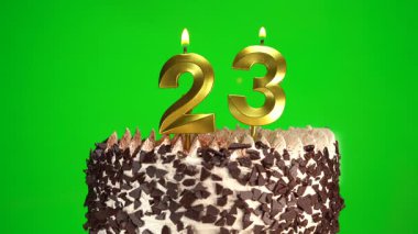 Çikolatalı doğum günü pastasında mum yakmak yeşil krom anahtar arka planda 23 numaralı altın mumla. 23 yıldır doğum günü pastasını kutluyoruz. Boşluğu kopyala