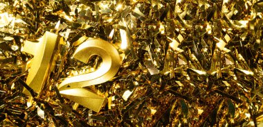 Doğum gününü kutlamak için 12 numaralı altın mum, süslü püslü arka planda. 12. yaş günü. Doğum günü kutlaması kavramı. Boşluğu kopyala