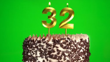 Çikolatalı doğum günü pastasında mum yakmak yeşil krom anahtar arka planda 32 numaralı altın mumla. 32 yıldır doğum günü pastasını kutluyoruz. Boşluğu kopyala