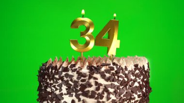 Çikolatalı doğum günü pastasında mum yakmak yeşil krom anahtar arka planda 34 numaralı altın mumla. 34 yıldır doğum günü pastasını kutluyoruz. Boşluğu kopyala