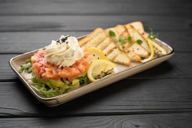 Limonlu krem peynirli somon ve avokado salatası ve çıtır ekmek tostlu siyah susam. Taze sağlıklı yemek, hafif öğle yemeği veya aperatif, gurme restoran menüsü..