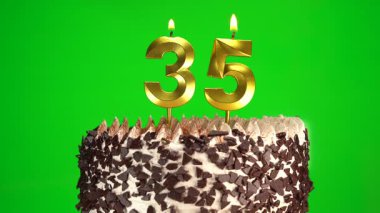 Yeşil krom anahtar arka planında 35 numaralı altın mumla çikolatalı doğum günü pastasında mum yakmak. 35 yıldır doğum günü pastasını kutluyoruz. Boşluğu kopyala