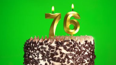 Doğum günü pastasında krom anahtar arka planında 76 numaralı mumları yakmak. Yetmiş altıncı yaş günü. Doğum günü kutlaması kavramı