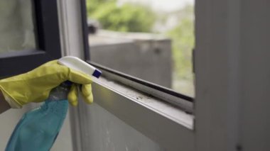 Sarı eldivenli tozla pencereyi temizliyorum. Sıvı püskürtme. Ev işleri ve ev idaresi kavramı