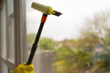 Pencere temizleme fırçası. Dairede paspasla pencereyi temizleyen bir kadın. temizlik kavramı