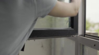 Kadın hademe dairede cam pencere yıkıyor. Temizlik hizmeti konsepti. Yakın plan.