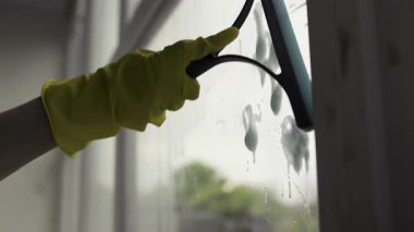 Ofisin camlarını özel bir aletle temizleyen kadın bir temizlikçi. Yakın plan.