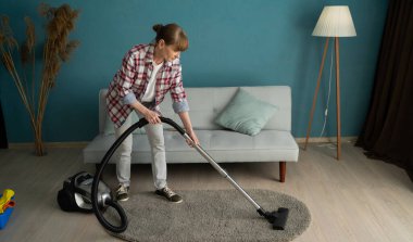 Ev temizliği konsepti. Kadın ev hanımı elektrikli süpürgeyle evi temizliyor. Boşluğu kopyala