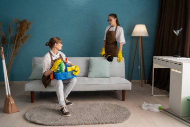 Ev ya da apartmanda çalışan hizmetliler. Kadın temizlikçiler işten sonra oturma odasında mola veriyorlar. Boşluğu kopyala