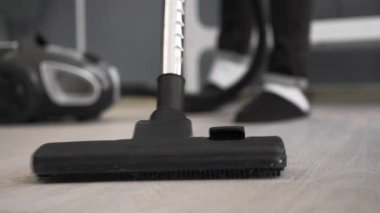 Temizlikçi, yerleri elektrikli süpürgeyle süpürüyor. Oda temizliği konsepti. Yakın plan.