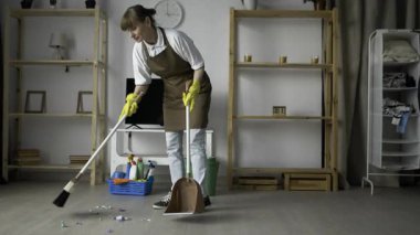 Temizlikçi oturma odasında süpürgeyle yerleri süpürüyor. Temizlik hizmeti kavramı