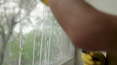 Temizlik için pencereyi sprey ve paçavra ile yıkıyorum. Yakın plan. Dezenfeksiyon servisi. Oda servisi ve ev işi kavramı